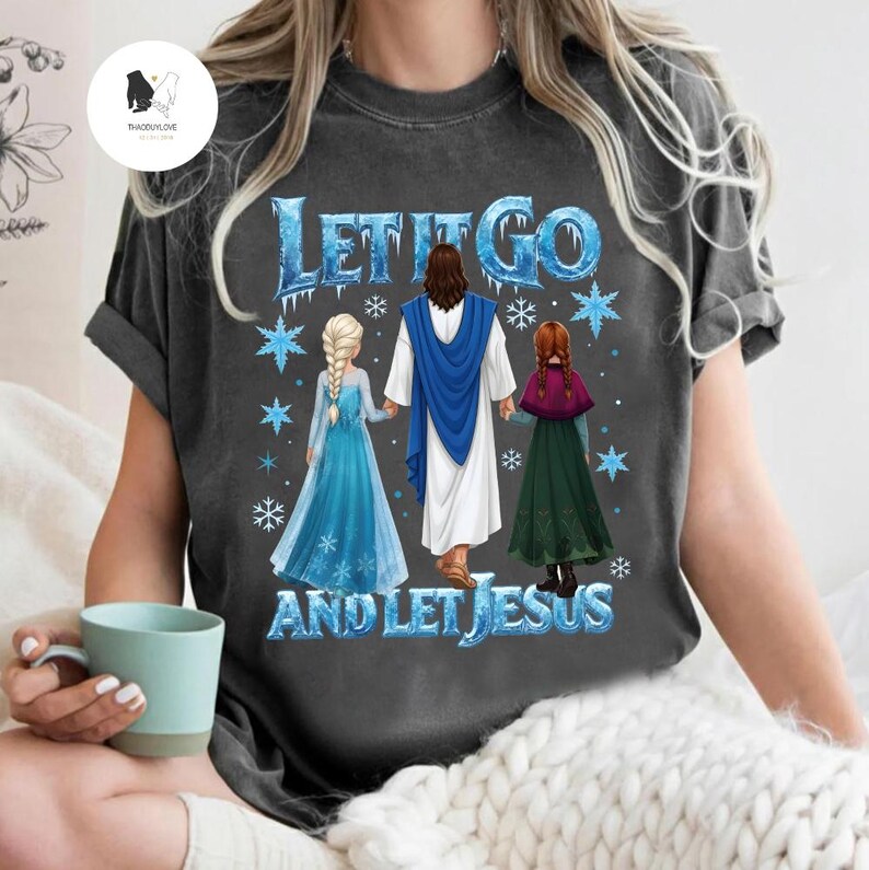 May include: Dark gray t-shirt with the text "LET IT GO AND LET JESUS" in blue and white. The graphic features Jesus holding hands with two cartoon characters in blue and green dresses, with snowflakes.