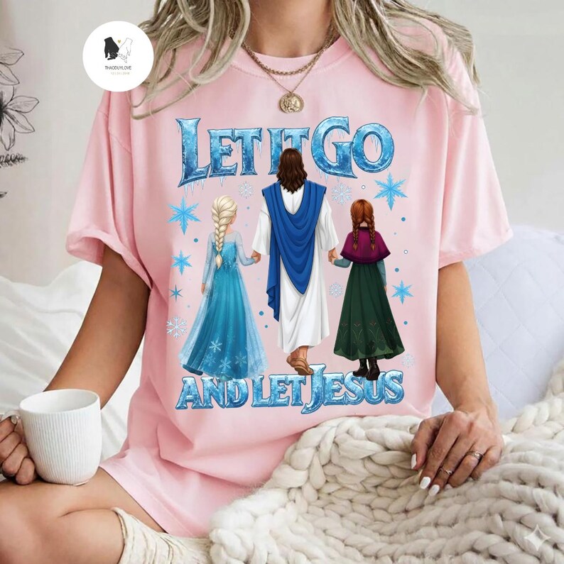 May include: Pink t-shirt with the text "LET IT GO AND LET JESUS" in blue. The graphic features Jesus holding hands with two cartoon characters in a blue dress and a green dress, with snowflakes.
