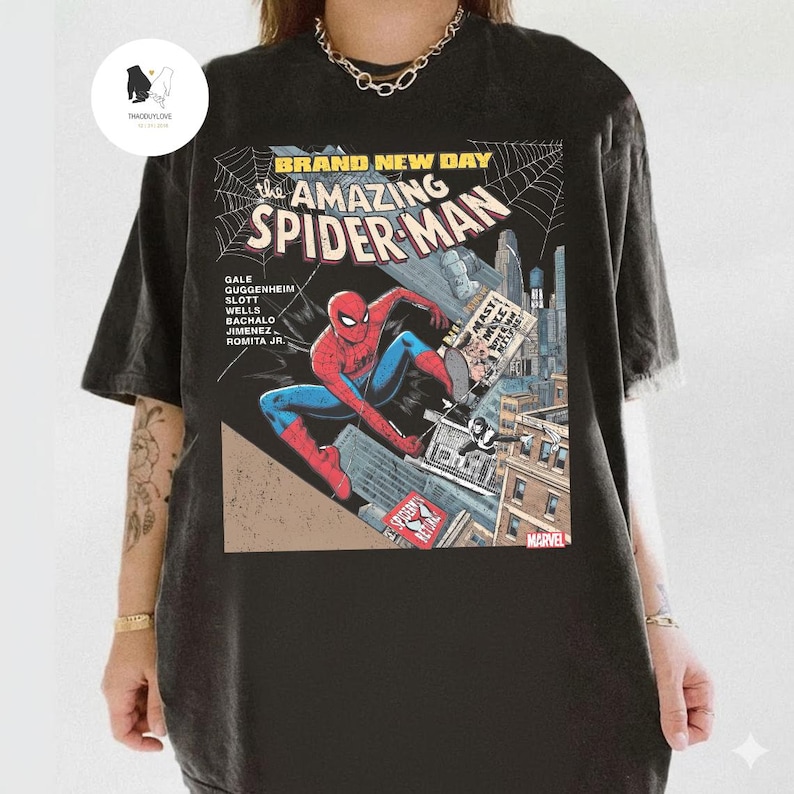 Puede incluir: Camiseta negra con un dise&ntilde;o de portada de c&oacute;mic de Spider-Man. El gr&aacute;fico incluye el texto "BRAND NEW DAY" y "the AMAZING SPIDER-MAN". El superh&eacute;roe se representa en una pose din&aacute;mica con un fondo de paisaje urbano. El logotipo de Marvel es visible.