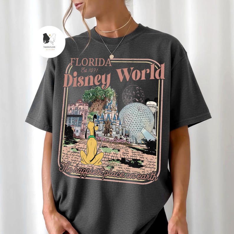 Puede incluir: Camiseta gris oscuro con un gr&aacute;fico de estilo vintage de Florida Disney World. El dise&ntilde;o incluye a Pluto, el castillo de Cenicienta y Spaceship Earth, con el texto "Florida Disney World" y "The happiest place on earth."