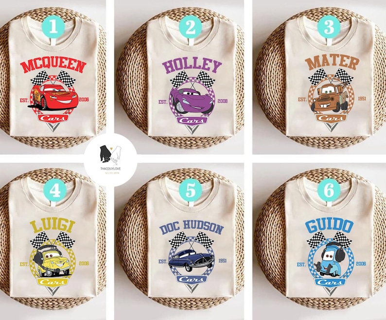 May include: Six white t-shirts featuring different Cars characters. Each shirt has a chequered flag design and the text "Cars" below the character. The characters are McQueen, Holley, Mater, Luigi, Doc Hudson, and Guido.