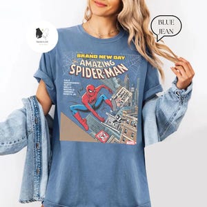 Puede incluir: Camiseta azul con un gr&aacute;fico de c&oacute;mic de Spider-Man. El gr&aacute;fico incluye el texto "BRAND NEW DAY the AMAZING SPIDER-MAN" y los nombres de los creadores del c&oacute;mic. La camiseta tiene mangas cortas y un corte relajado.