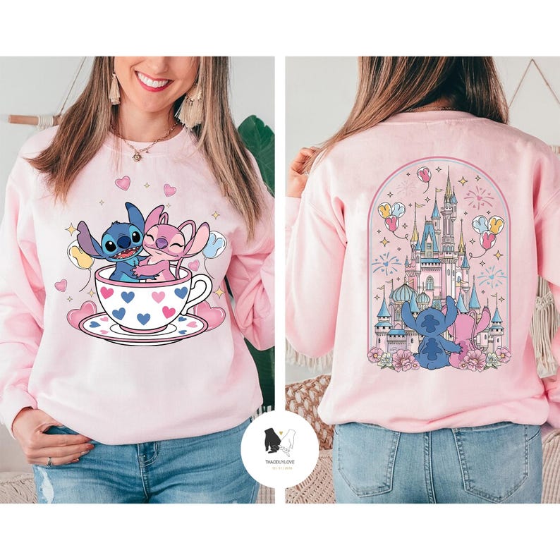 May include: Pink sweatshirt featuring a cartoon design of Stitch and Angel in a teacup with hearts. The back of the sweatshirt shows a castle with Stitch and Angel. The sweatshirt has long sleeves and a crew neck.