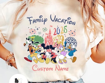 May include: Cream-colored t-shirt featuring a colorful graphic of Disney characters, including Mickey and Minnie Mouse, Goofy, Donald and Daisy Duck. The text "Family Vacation 2025" is above the characters, with "Custom Name" below.