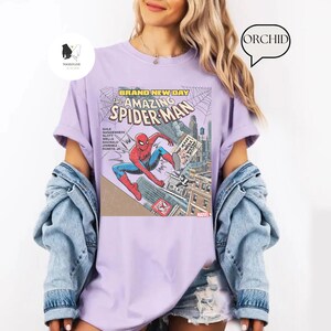 Puede incluir: Camiseta lila claro con una ilustraci&oacute;n de c&oacute;mic de Spider-Man. El gr&aacute;fico es de la historieta "The Amazing Spider-Man", con las palabras "Brand New Day". La camiseta tiene mangas cortas y un corte holgado.