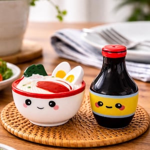 Può includere: Una tazza di ceramica bianca con manico nero e la scritta "But First, Coffee" in grassetto nero. La tazza è posta su uno sfondo sfocato, che suggerisce un'atmosfera accogliente.