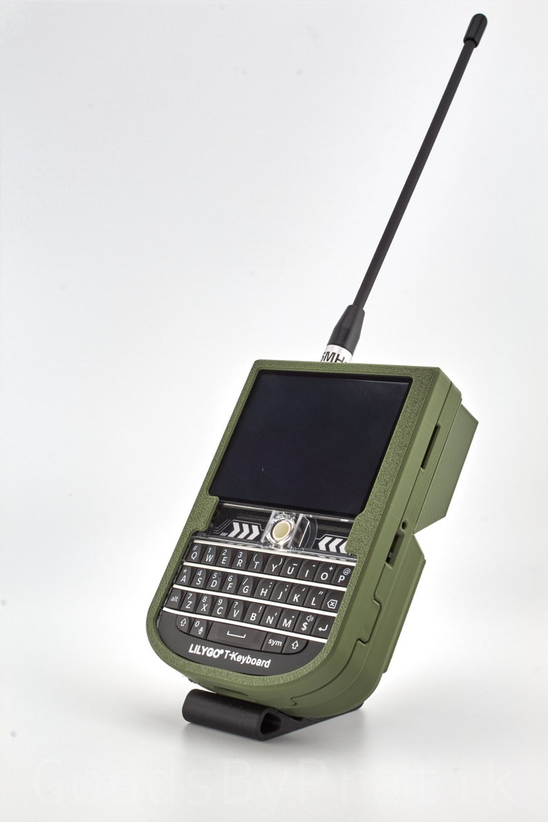 K&ouml;nnte beinhalten: Ein gr&uuml;nes, robustes Smartphone mit einer schwarzen Antenne, einer schwarzen Tastatur und dem Text "LILYGOT-Keyboard" unten.