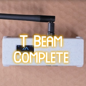May include: A white rectangular device with a black antenna and the text "T BEAM COMPLETE" in yellow letters.