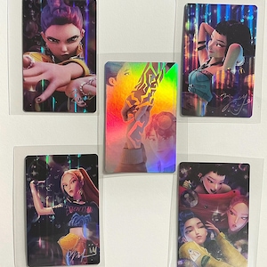 May include: Five rectangular holographic trading cards featuring stylized digital illustrations of characters. Each card displays a unique character portrait with vibrant colors, metallic sheen, and printed signatures, all individually encased in clear plastic sleeves.