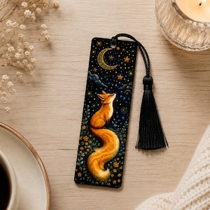 May include: A rectangular bookmark featuring a vibrant orange fox sitting amidst small yellow flowers under a dark blue night sky filled with stars and a crescent moon. The bookmark includes a black cord tassel attached at the top center.