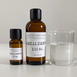 Peut inclure: Image de matériel de laboratoire comprenant deux flacons en verre brun avec des bouchons noirs et des étiquettes blanches, et un bécher en verre transparent. Les flacons sont étiquetés "BENZALDEHYDE" avec des mesures de volume de 20 ml et 100 ml. Le bécher contient un liquide clair.