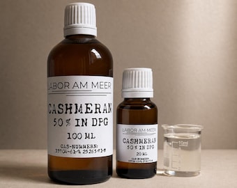 Può includere: Due flaconi in vetro ambrato con tappi bianchi ed etichette bianche con la scritta LABOR AM MEER CASHMERAN 50% IN DPG. Il flacone grande è da 100 ml e quello piccolo da 20 ml. Un misurino trasparente con tacche da 10 ml è accanto al flacone.