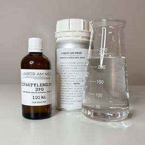 May include: An image of laboratory equipment including a brown glass bottle labeled "DIPROPYLENGLYCOL DPG 100 ML", a silver container, and a clear glass beaker with liquid. The beaker has measurements in milliliters.