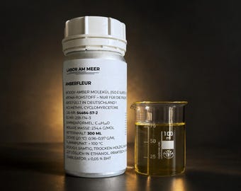 Może przedstawiać: Butelka z białą plastikową nakrętką z etykietą AMBERFLEUR, danymi technicznymi i objętością netto 300 ml, obok przezroczystej szklanej zlewki laboratoryjnej zawierającej żółty płyn z podziałką do 100 ml.
