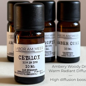 May include: Four amber glass bottles with black caps. The bottles have white labels with black text, including "CETALOX 10% IN DPG 10 ML" and "LABOR AM MEER." Additional text reads "Ambery Woody Dry, Warm Radiant Diffusive, High diffusion booster."