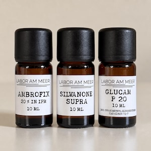 May include: Three small amber glass bottles with black screw-on caps, each featuring a white label with the text LABOR AM MEER. The labels identify the contents as AMBROFIX 20% IN IPM, SILVANONE SUPRA, and GLUCAM P 20, each containing 10 ml of liquid.