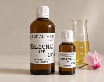Può includere: Due flaconi in vetro ambrato con tappi bianchi ed etichette con la scritta Labor Am Meer Helional IFF, da 100 ml e 20 ml. Accanto si trovano una beuta in vetro trasparente contenente liquido giallo e un singolo fiore di ciclamino rosa con stelo.