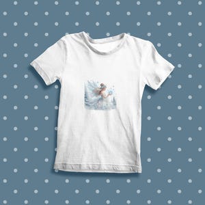 May include: White t-shirt with a watercolor illustration of a fairy holding a snowflake in a snowy forest setting.