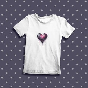 May include: White t-shirt with a galaxy-themed heart design. The heart is pink, purple, and black with white stars and a dripping effect.