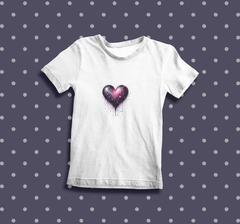 May include: White t-shirt with a galaxy-themed heart design. The heart is pink, purple, and black with white stars and a dripping effect.