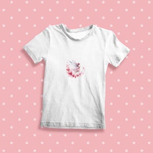Peut inclure: T-shirt blanc avec un motif aquarelle d'une f&eacute;e volant dans un cercle de c&oelig;urs roses.