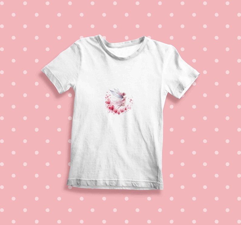 Peut inclure: T-shirt blanc avec un motif aquarelle d'une f&eacute;e volant dans un cercle de c&oelig;urs roses.