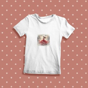 May include: White t-shirt with a watercolor illustration of a woman in a red dress with her arms raised.