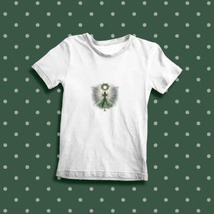 May include: White t-shirt with a green fairy illustration wearing a crown and holding a glowing orb. The fairy has wings and is surrounded by a halo of light.