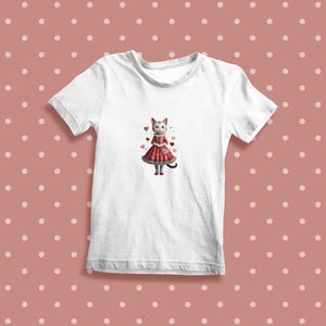 May include: White t-shirt with a graphic of a cat wearing a red dress and holding a heart. The cat is surrounded by pink hearts.