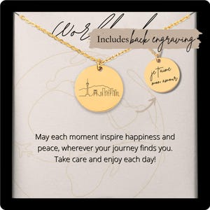 May include: A gold-colored necklace with two circular pendants. One pendant features a city skyline, and the other has the phrase "je t'aime mon amour." The text "Includes back engraving" is also visible.