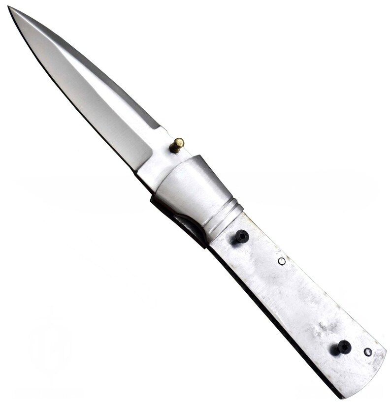 May include: A stainless steel folding knife with a polished blade. The knife has a silver handle with black rivets and a brass-colored pin. The blade is pointed and angled.