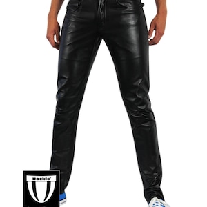 May include: Black leather trousers with a classic five-pocket design. The trousers have a button and zip closure and are worn with blue trainers. The brand logo "Bockle" is visible on the lower left.