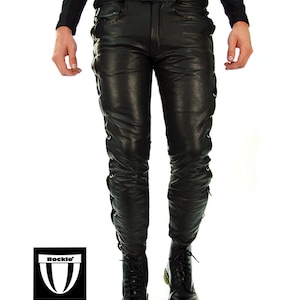 May include: Black leather pants with lace-up detailing on the sides. The pants have a slim fit and are worn with black leather boots.