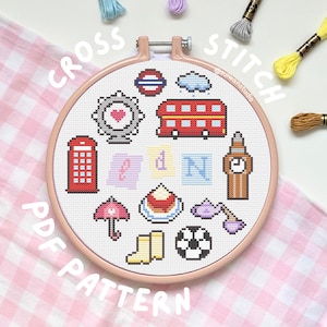May include: A cross-stitch PDF pattern featuring London-themed icons like a red double-decker bus, Big Ben, and a telephone booth. The design is in a round hoop with the words "CROSS STITCH PDF PATTERN" around the edge. Colorful embroidery floss is scattered around.