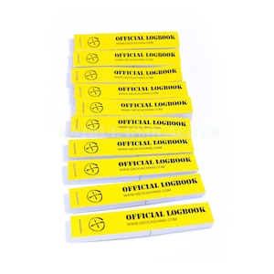 Puede incluir: Una pila de diez libretas de papel amarillas para geocaching. Cada libreta tiene un símbolo de brújula negro y el texto "OFFICIAL LOGBOOK" y "WWW.GEOCACHING.COM".