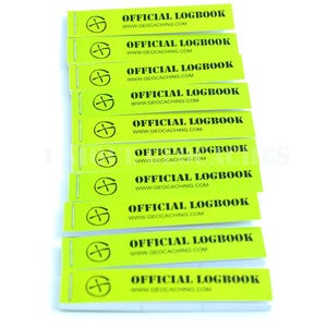 Puede incluir: Una pila de diez libretas de registro de color verde brillante con texto negro que dice "OFFICIAL LOGBOOK" y "WWW.GEOCACHING.COM".