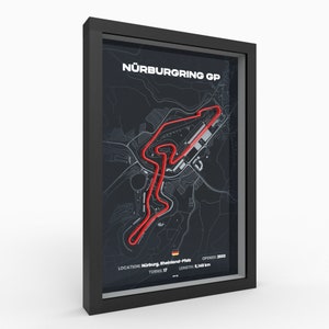 Puede incluir: Una impresión enmarcada en negro del circuito de carreras Nürburgring GP en Alemania. La pista está delineada en rojo en un mapa en blanco y negro. La impresión incluye la ubicación de la pista, el número de curvas, la longitud y el año de apertura. "NÜRBURGRING GP" es el título de la impresión.