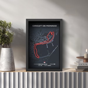 May include: A black framed poster with a red line tracing the Circuit de Monaco race track. The poster includes the text "CIRCUIT DE MONACO", "LOCATION: Monte Carlo, Monaco", "TURNS: 19", "OPENED: 1929", and "LENGTH: 3.337 m".