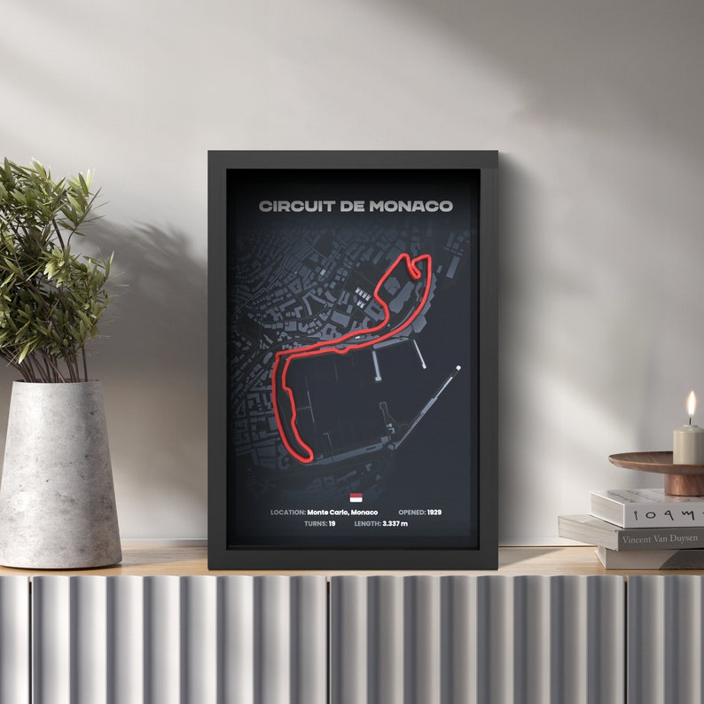 May include: A black framed poster with a red line tracing the Circuit de Monaco race track. The poster includes the text "CIRCUIT DE MONACO", "LOCATION: Monte Carlo, Monaco", "TURNS: 19", "OPENED: 1929", and "LENGTH: 3.337 m".