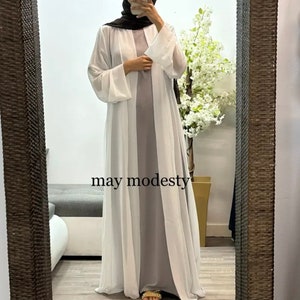 May include: A white sheer long-sleeved cardigan with a gray maxi dress underneath. The text "may modesty" is visible on the dress.