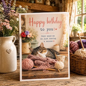 May include: A rectangular birthday greeting card featuring a sleeping tabby cat resting on a pink knitted blanket with yarn balls and knitting needles. The text reads: Happy birthday to you! Dont mind me im just having a snooze.