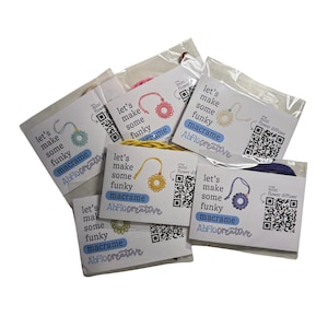 May include: A collection of macrame kits in clear plastic packaging. Each kit features a card with the text "let's make some funky macrame" and a QR code. The kits contain colorful cords and a mini flower diffuser.