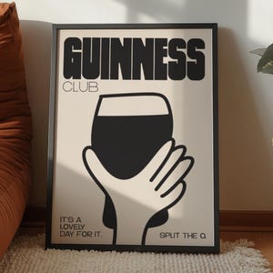 Pu&ograve; includere: Poster con cornice nera con la scritta "GUINNESS CLUB" in nero. Il poster presenta una grafica nera di una mano che tiene una pinta di Guinness. &Egrave; incluso anche il testo "IT'S A LOVELY DAY FOR IT. SPLIT THE Q".