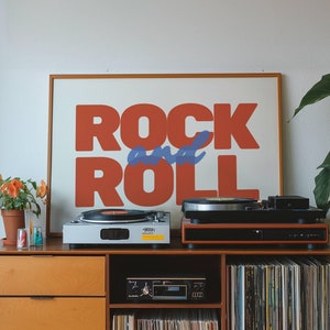 May include: A wooden cabinet with a record player, a turntable, and a record collection. The cabinet has a poster above it that says "Rock and Roll" in red and blue letters.