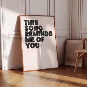 May include: A framed print with the text "THIS SONG REMINDS ME OF YOU" in black bold letters on a white background.