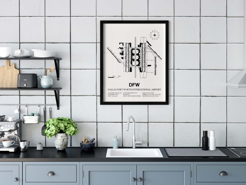 May include: Black and white print of the Dallas Fort Worth International Airport layout, with the text "DFW" and "Dallas Fort Worth International Airport" below the map. The print is framed in black and hanging on a white tiled wall in a kitchen.