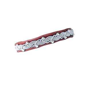 May include: A brown leather bracelet with a silver wire design. The silver wire is woven in a decorative pattern along the top of the bracelet. Small silver beads are evenly spaced along the design. The bracelet is approximately 0.75 inches wide.