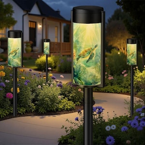 May include: Black outdoor pathway lights with a cylindrical design. Each light features a sea turtle image on the illuminated panel. The lights are set in a garden with colorful flowers and a pathway.