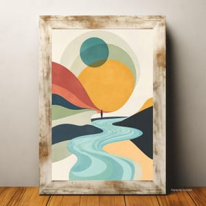 May include: Abstract art print featuring a person standing near a river, with a large yellow sun and colorful mountain range. The artwork is framed in a rustic, light-colored wooden frame. The art print is displayed on a wooden surface.