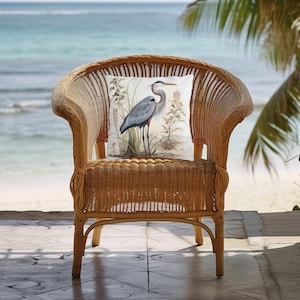 May include: A wicker chair with a throw pillow featuring a watercolor illustration of a blue heron standing in a marsh.